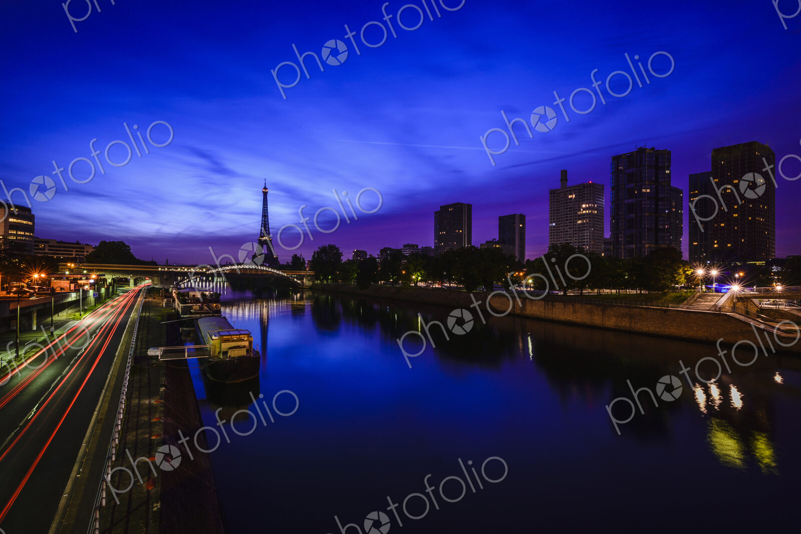 A view along the water of the River Seine at night, tall buildings on the river bank,…
