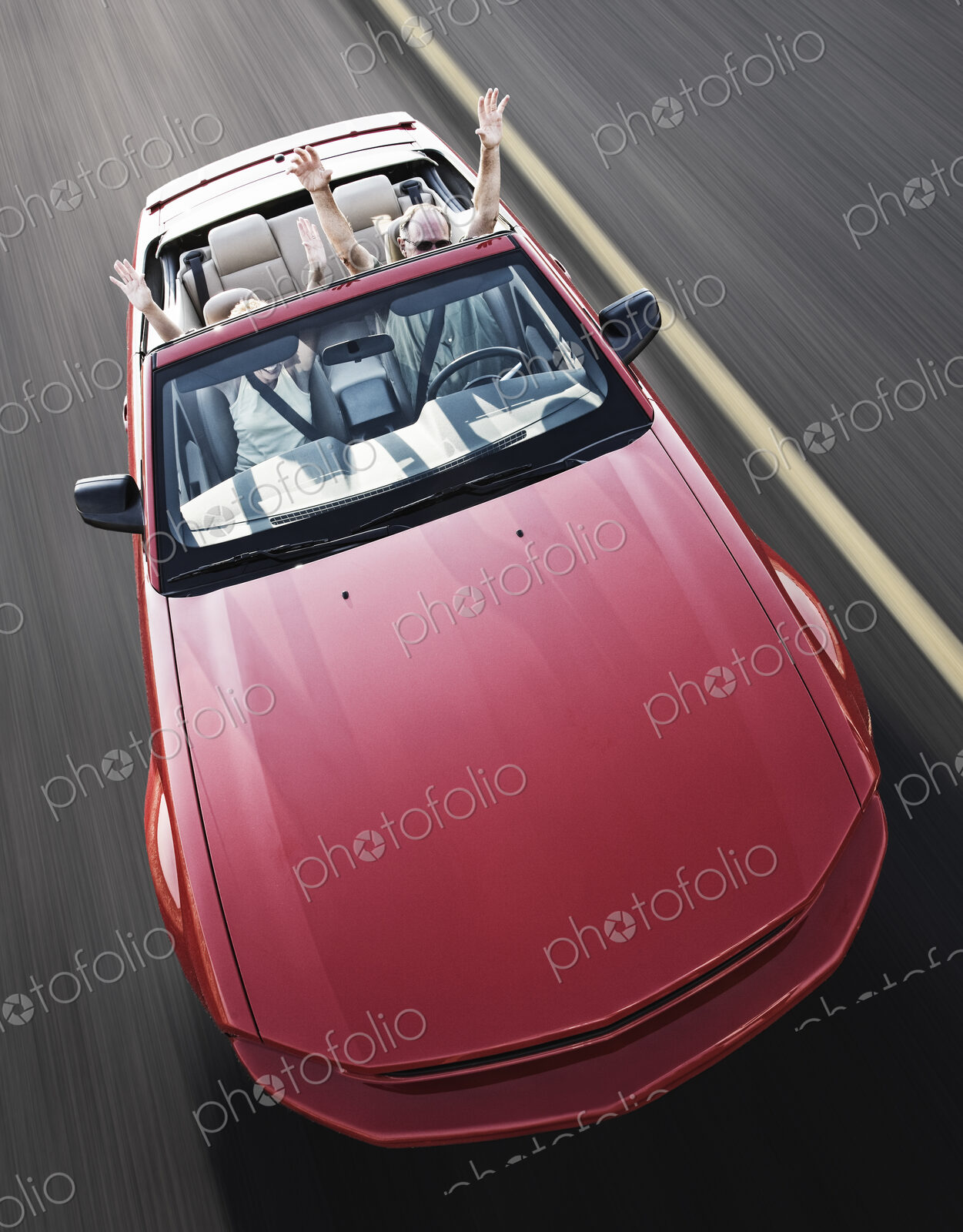 A view from above looking down on a convertible sports car and a Caucasian couple on a…