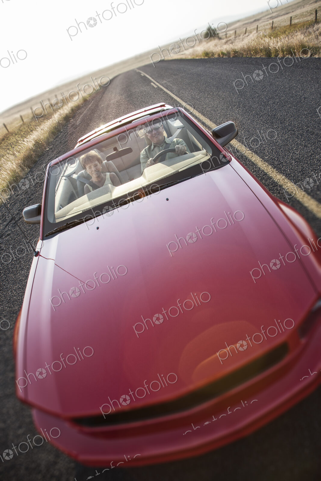A view from above looking down on a convertible sports car and a Caucasian couple on a…