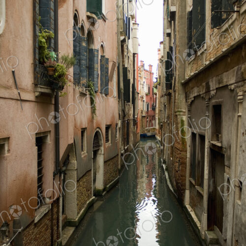 A view from above of a quiet backwater, a narrow canal with historic buildings rising…