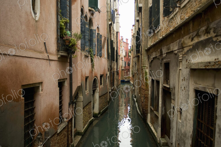 A view from above of a quiet backwater, a narrow canal with historic buildings rising…