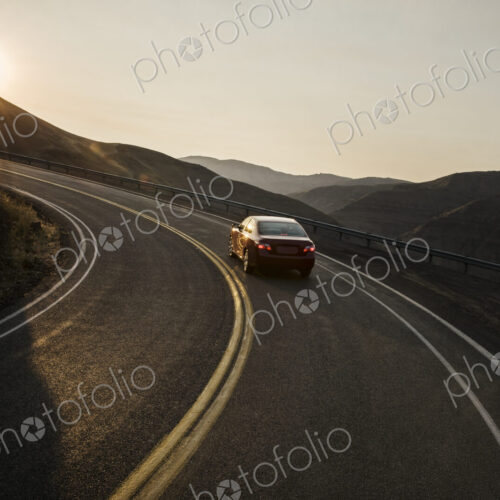 A view from behind of an automobile going around a curve at sunset in eastern… A view from behind of an automobile going around a curve at sunset in eastern…