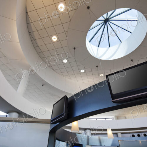 A view from below to a round dome ceiling with a central skylight. Display screens. A view from below to a round dome ceiling with a central skylight. Display screens.