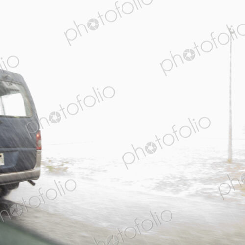 A view from inside a car of the monsoon rain falling on a road.