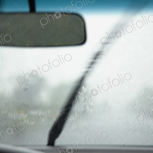 A view from inside a car of the monsoon rain falling on the wind-shield of the vehicle.