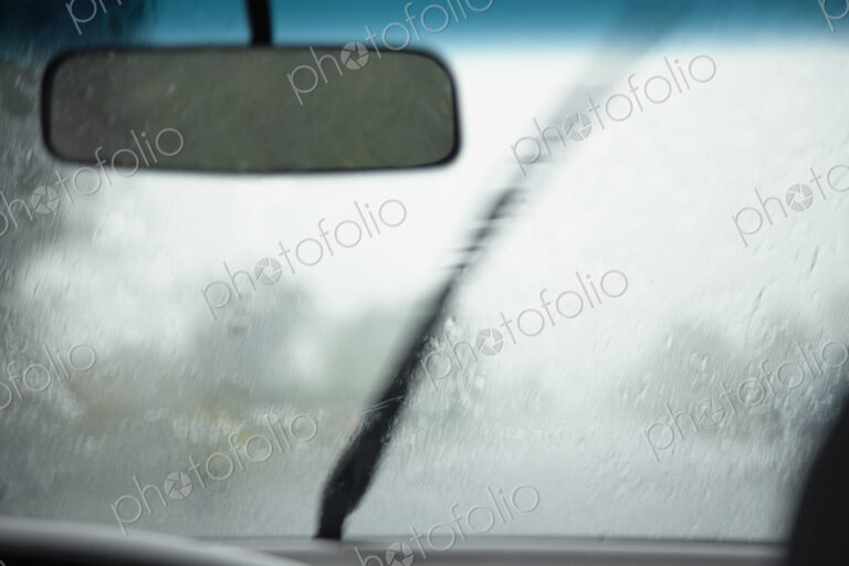 A view from inside a car of the monsoon rain falling on the wind-shield of the vehicle.