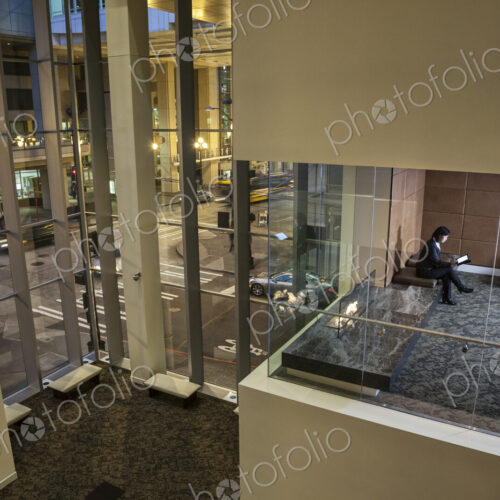 A view looking down into a conference room with a business woman looking at a notebook…