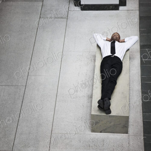 A view looking down on a businessman taking a break laying down on a bench. A view looking down on a businessman taking a break laying down on a bench.