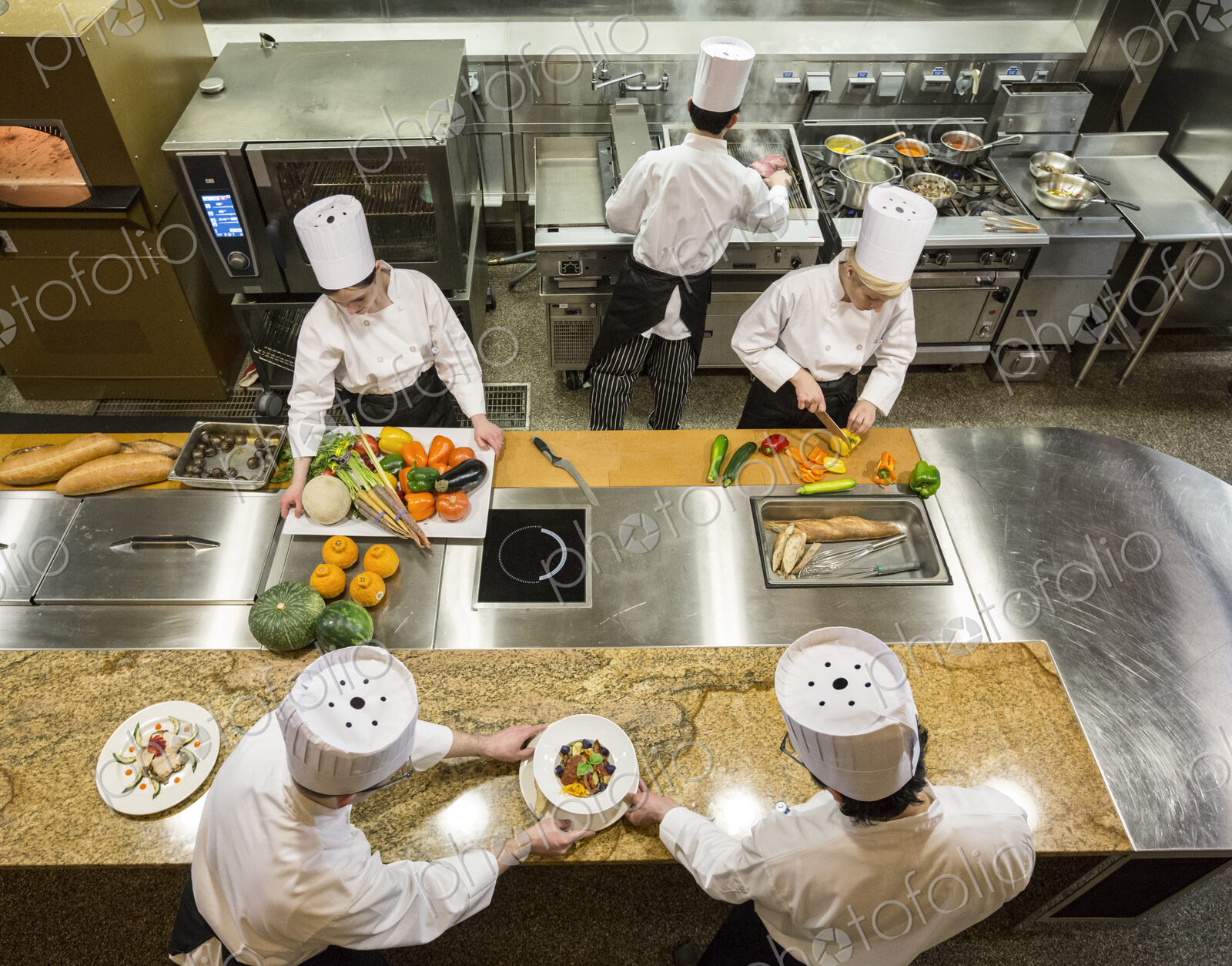 A view looking down on a crew of chefs working in a commercial kitchen,
