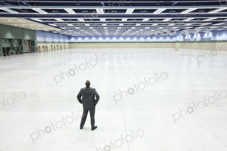 A view looking down on a single businessman surveying the interior of a convention…