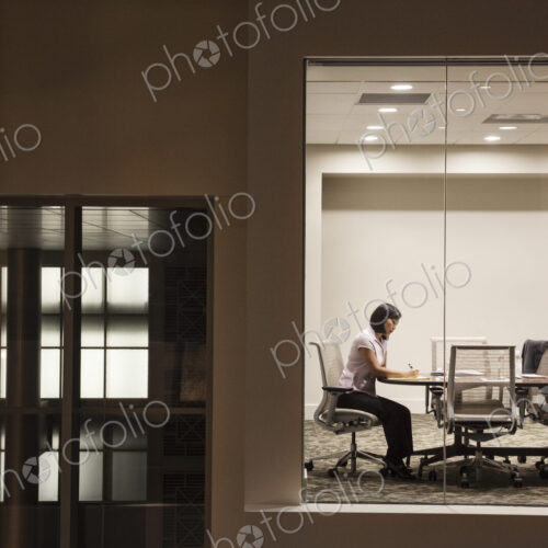 A view looking into a conference room at night of an Asian businesswoman.
