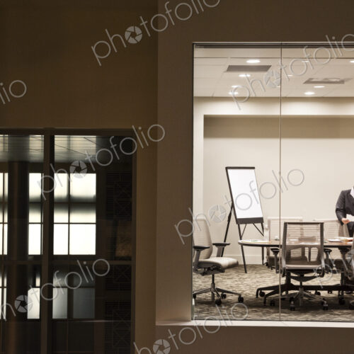 A view looking into a conference room at night of an Asian businesswoman.