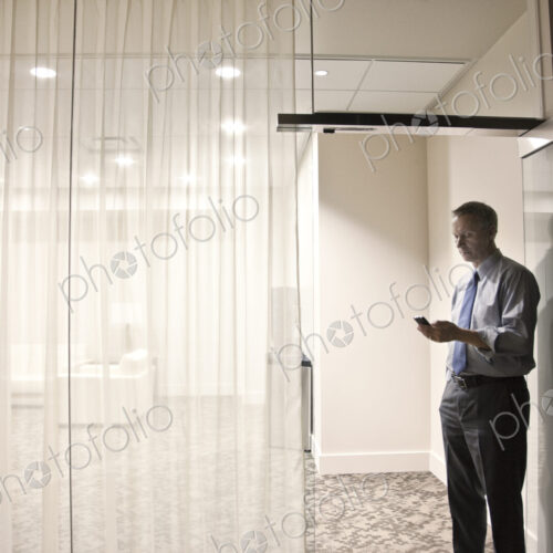 A view looking into a conference room of a businessman on his cell phone.