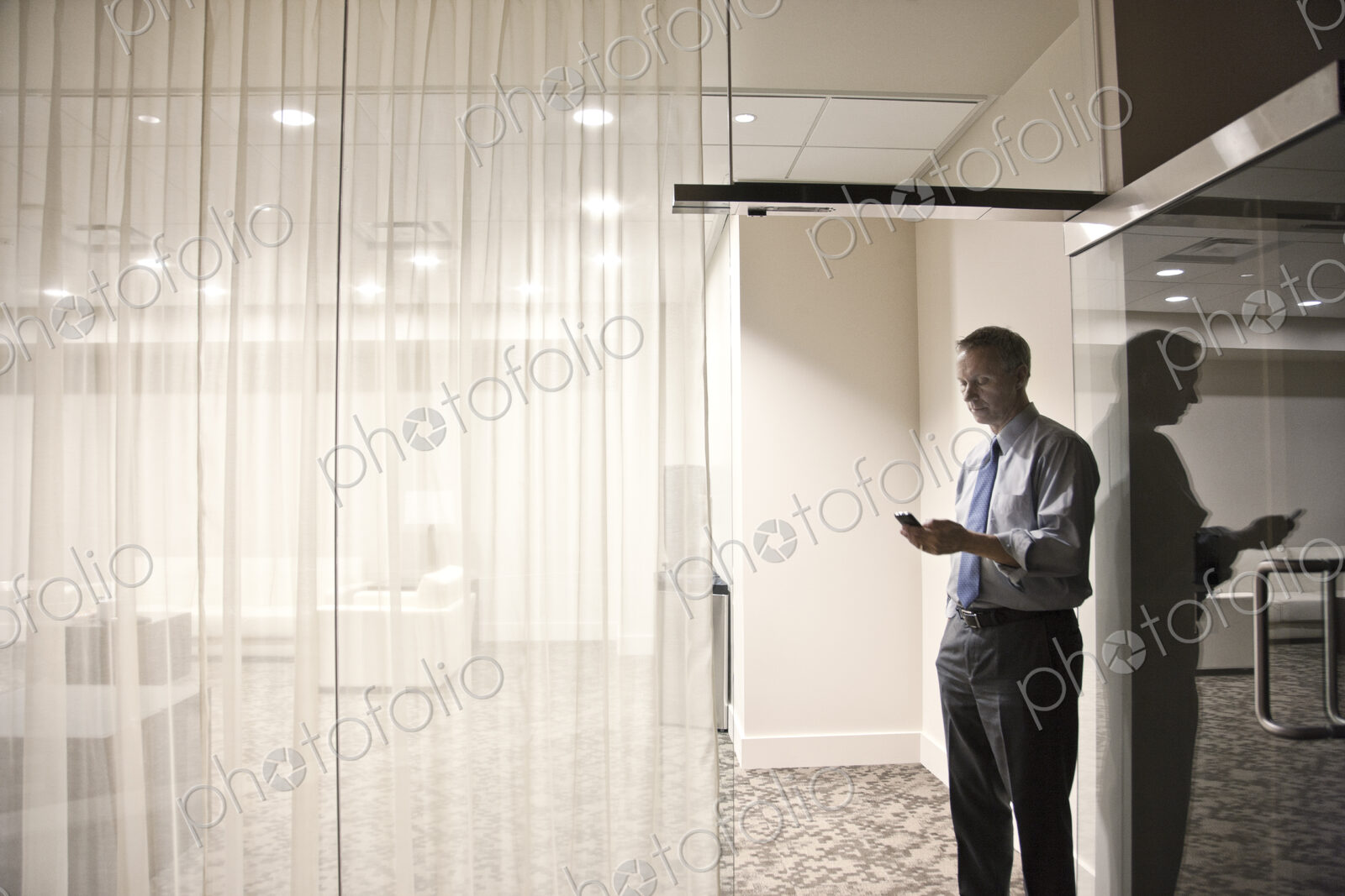 A view looking into a conference room of a businessman on his cell phone.