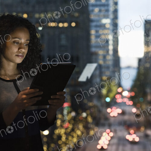 A view of a black businesswoman working on a digital tablet by a window with a city view A view of a black businesswoman working on a digital tablet by a window with a city view