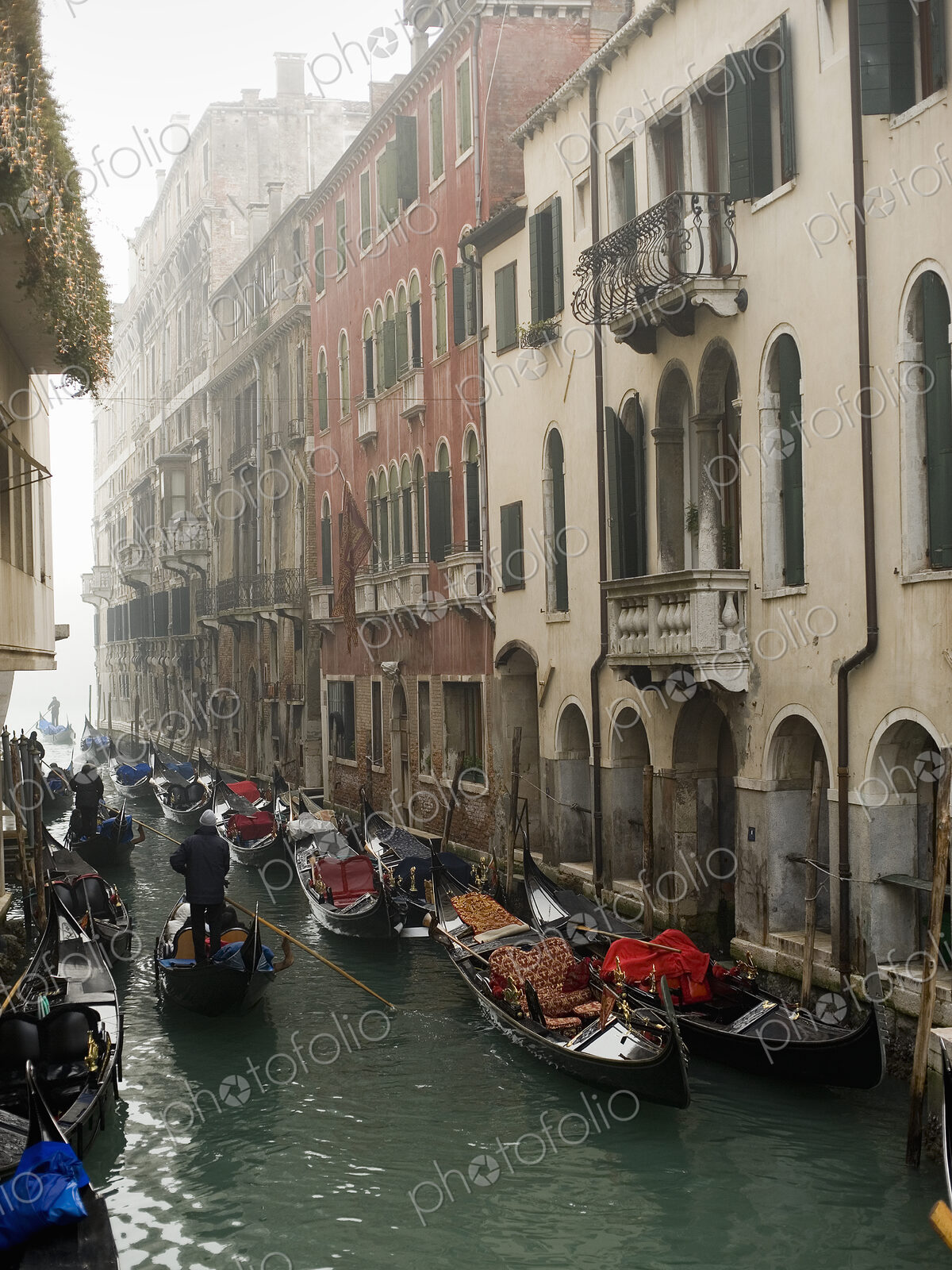 A view of a narrow canal crowded with boats and traditional gondolas, with historic…