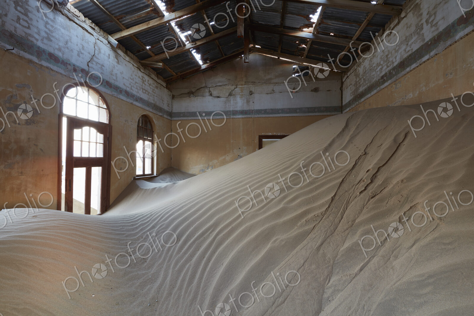 A view of a room in a derelict building full of sand.