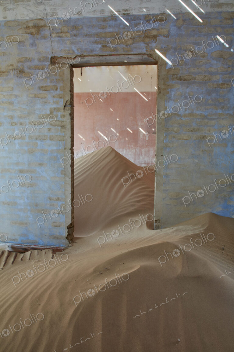 A view of a room in a derelict building full of sand.