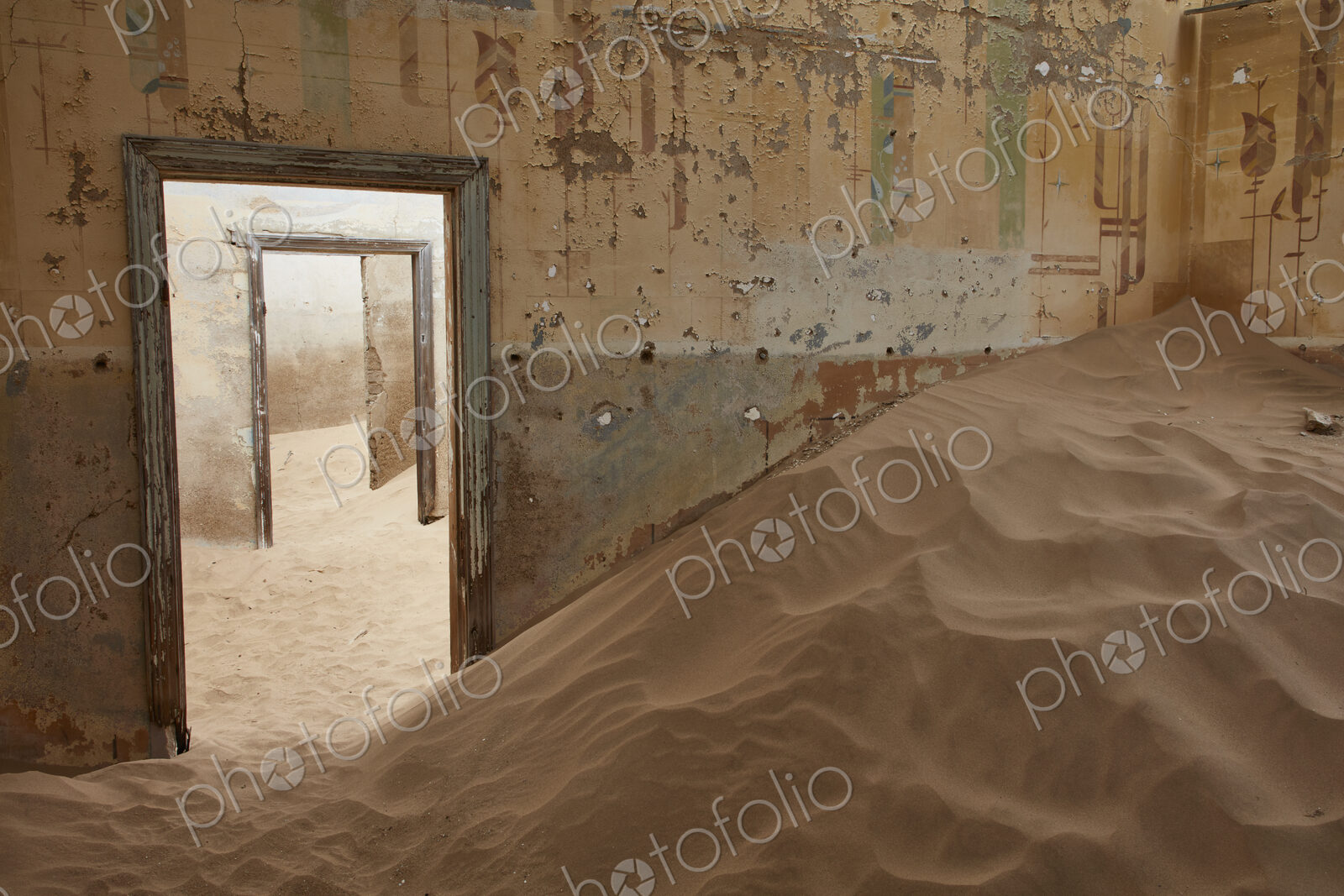 A view of a room in a derelict building full of sand.