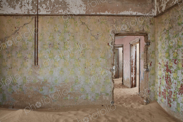 A view of a room in a derelict building full of sand.