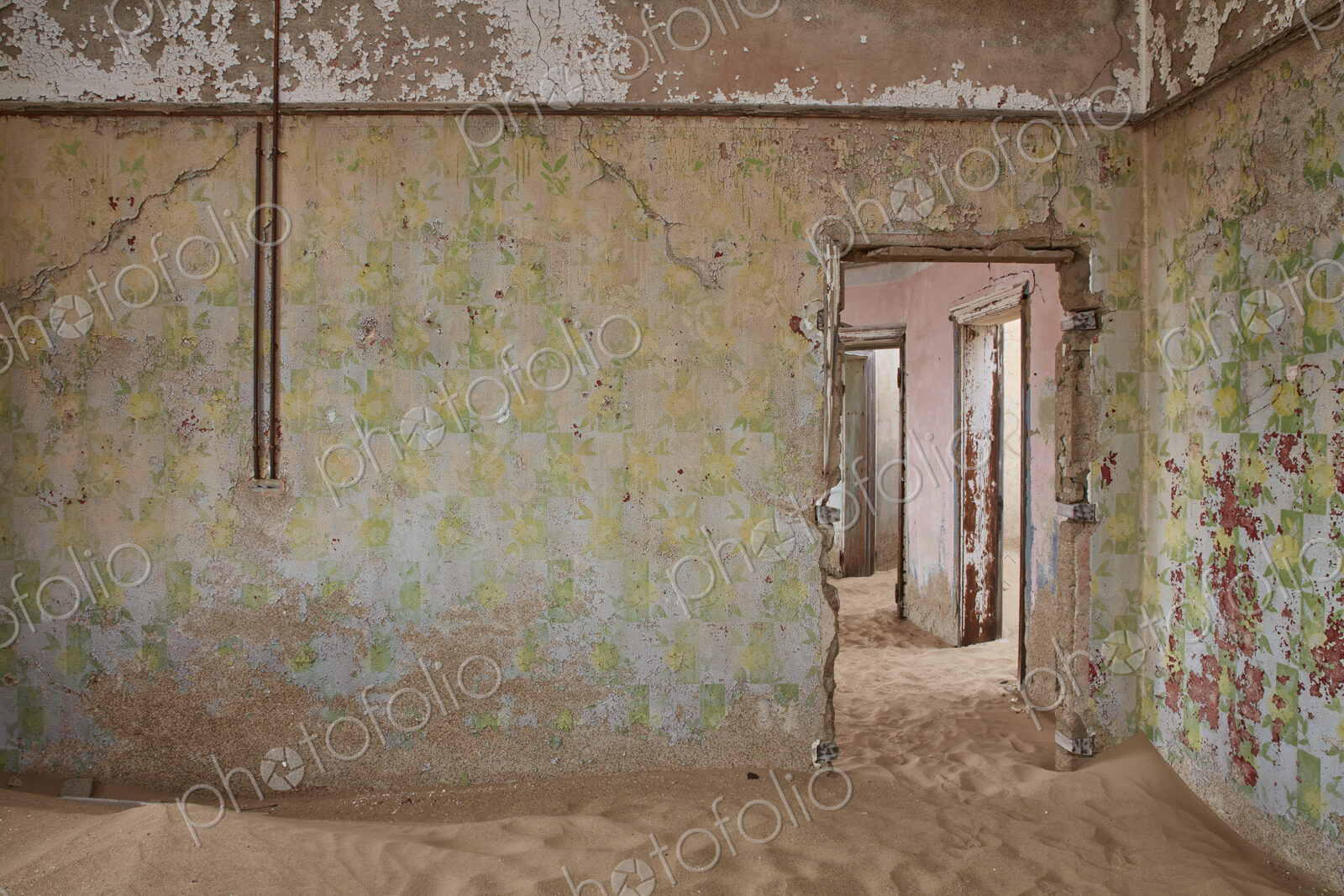 A view of a room in a derelict building full of sand.