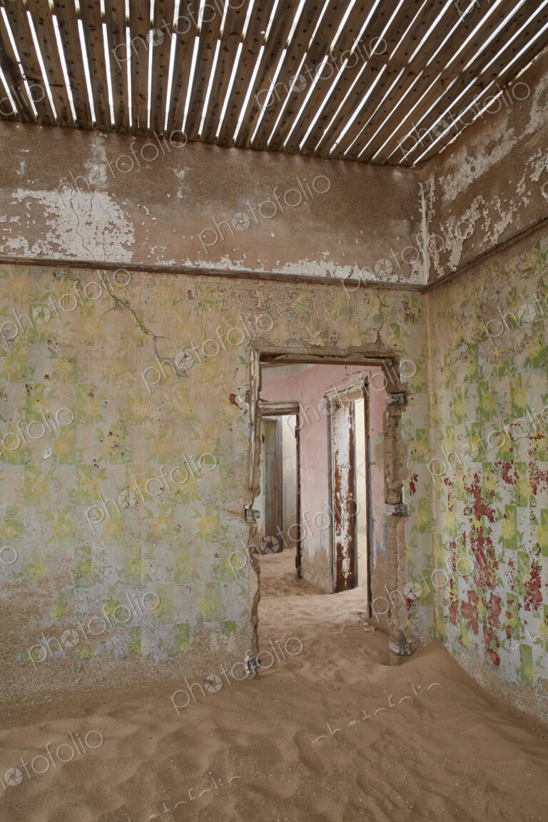 A view of a room in a derelict building full of sand.