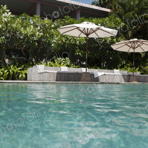 A view of the infinity swimming pool and umbrellas at a hotel.