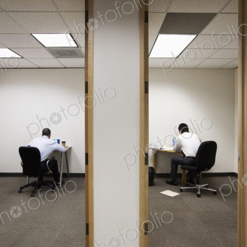 A view of two businessmen working on opposite sides of a wall in two different office… A view of two businessmen working on opposite sides of a wall in two different office…