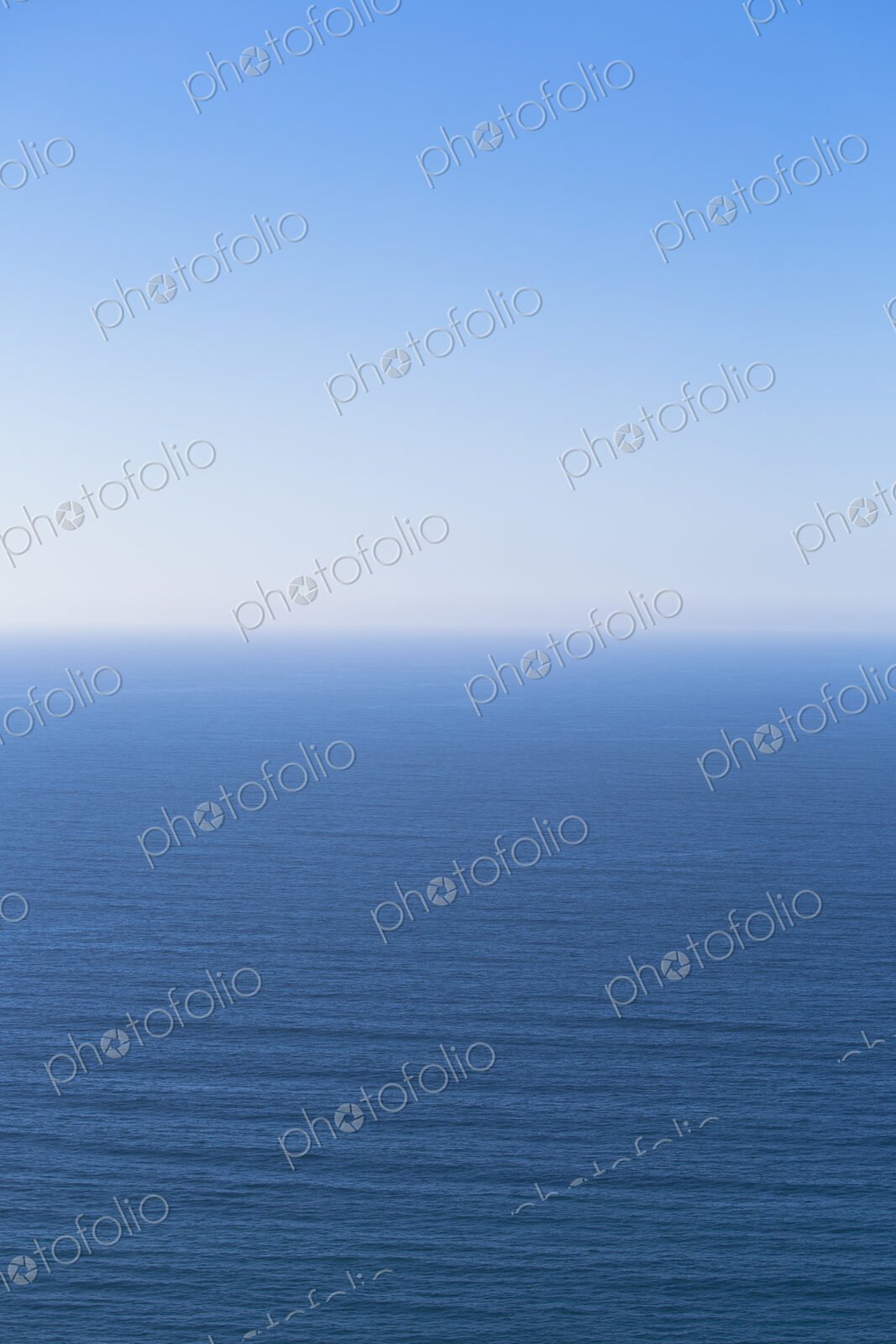 A view over the Pacific Ocean and a calm sea, merging into the blue sky.
