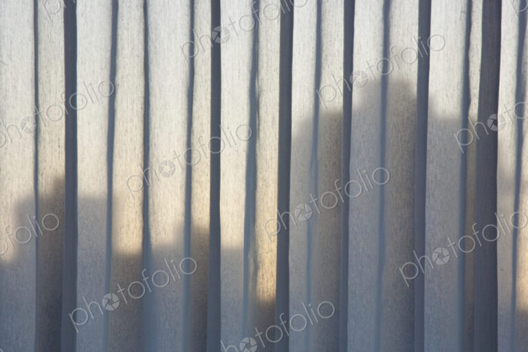 A view over the buildings of downtown Vancouver, shadows seem through vertical blinds…