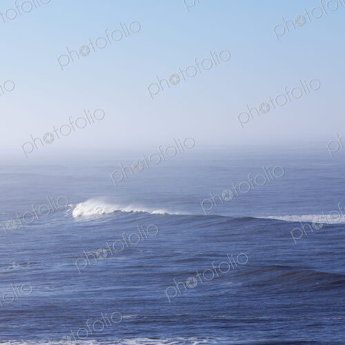 A view over the ocean, and a wave with a developing white crest. A view over the ocean, and a wave with a developing white crest.