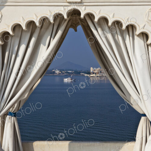 A view through a traditional scalloped edged archway, with curtains drawn back, view…