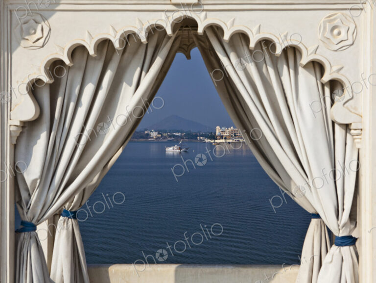 A view through a traditional scalloped edged archway, with curtains drawn back, view…