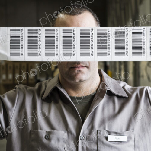 A warehouse worker holding up a sheet of bar code shipping lables in a distribution… A warehouse worker holding up a sheet of bar code shipping lables in a distribution…