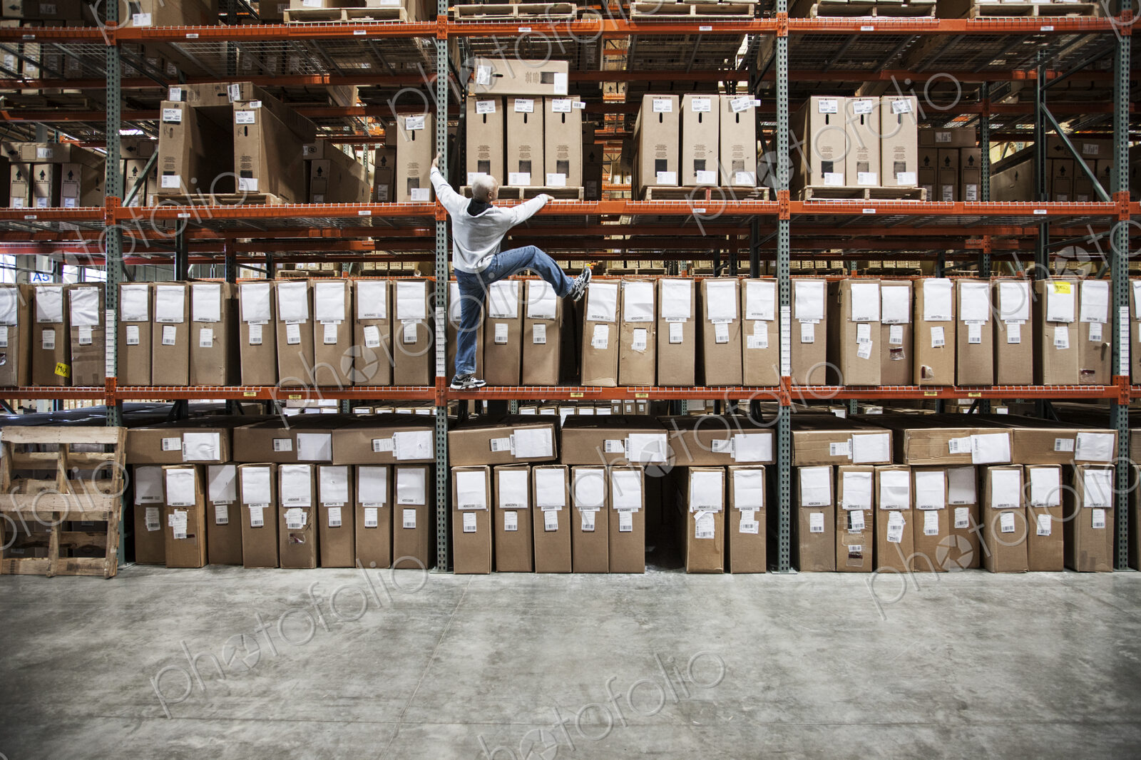A warehouse worker trying to climb a rack of products in a distribution warehouse.