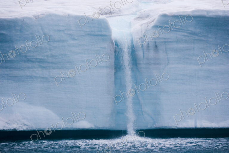 A waterfall is created by a melting iceberg, Svalbard, Norway