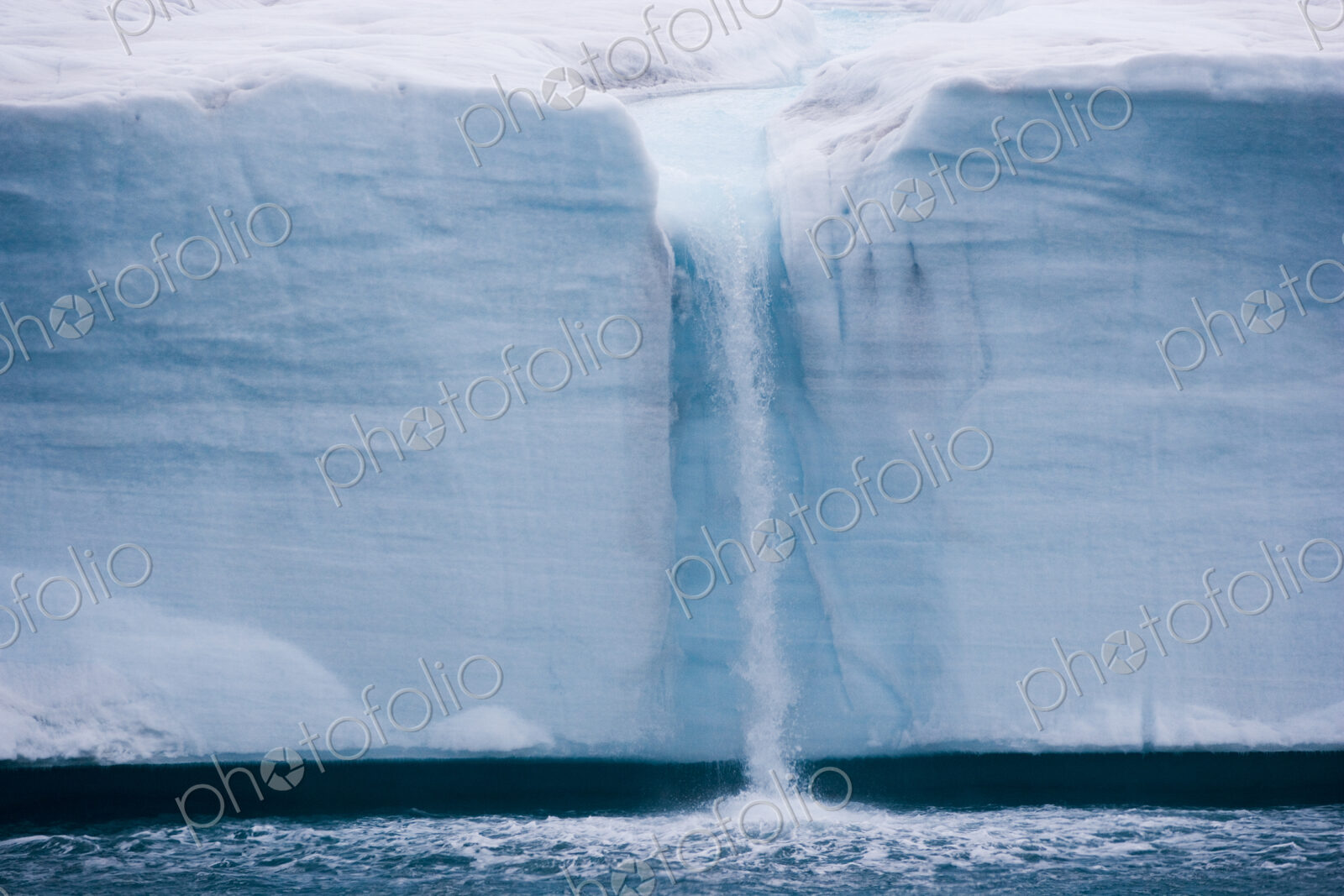 A waterfall is created by a melting iceberg, Svalbard, Norway