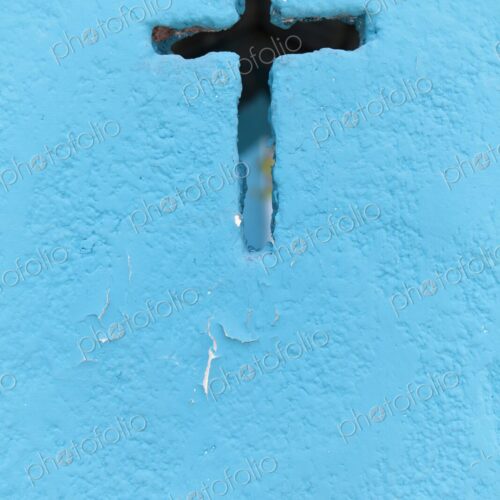 A weathered blue crypt wall with a cross-shaped cutout at a cemetery in Isla Mujeres.…