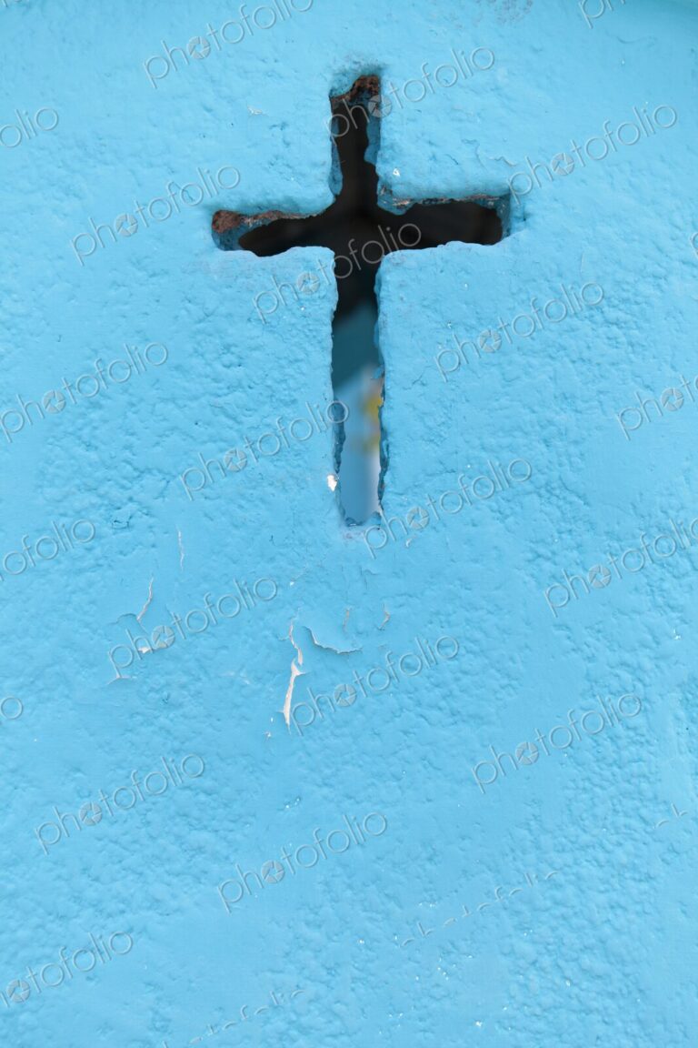 A weathered blue crypt wall with a cross-shaped cutout at a cemetery in Isla Mujeres.…