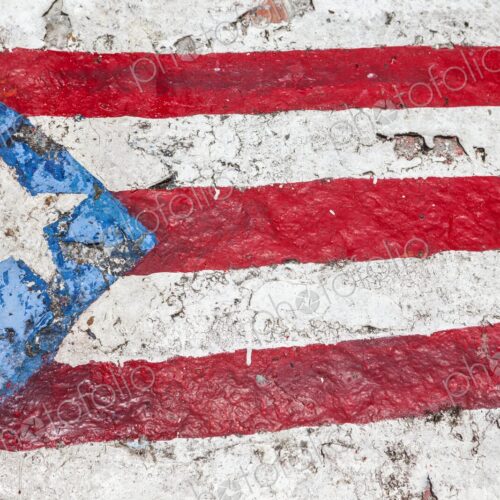A weathered painting of the Puerto Rican flag is shown on a textured rock surface at… A weathered painting of the Puerto Rican flag is shown on a textured rock surface at…