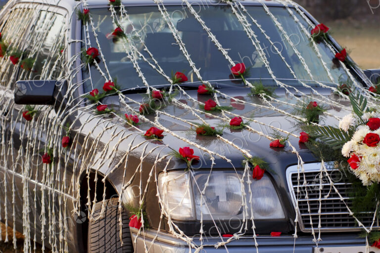 A wedding car decorated with red and white flowers.