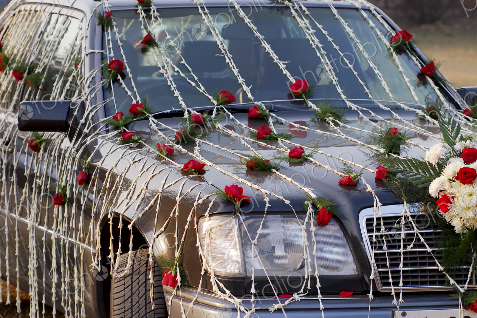 A wedding car decorated with red and white flowers.