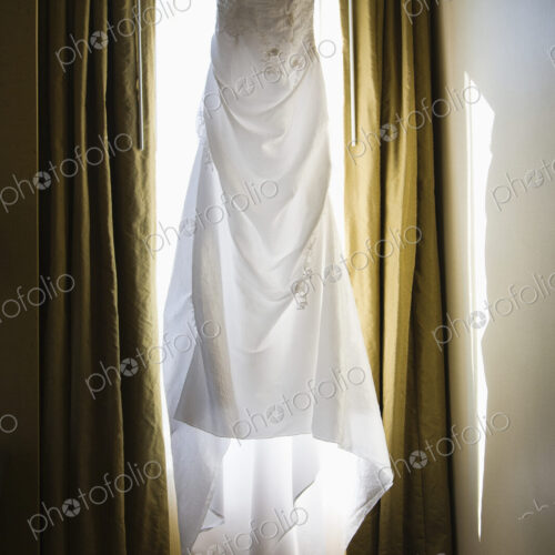 A wedding dress hanging up in a window A wedding dress hanging up in a window