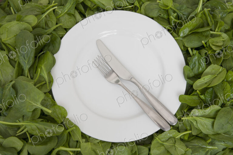 A white china plate with a knife and fork, resting on edible leaves. The concept of…