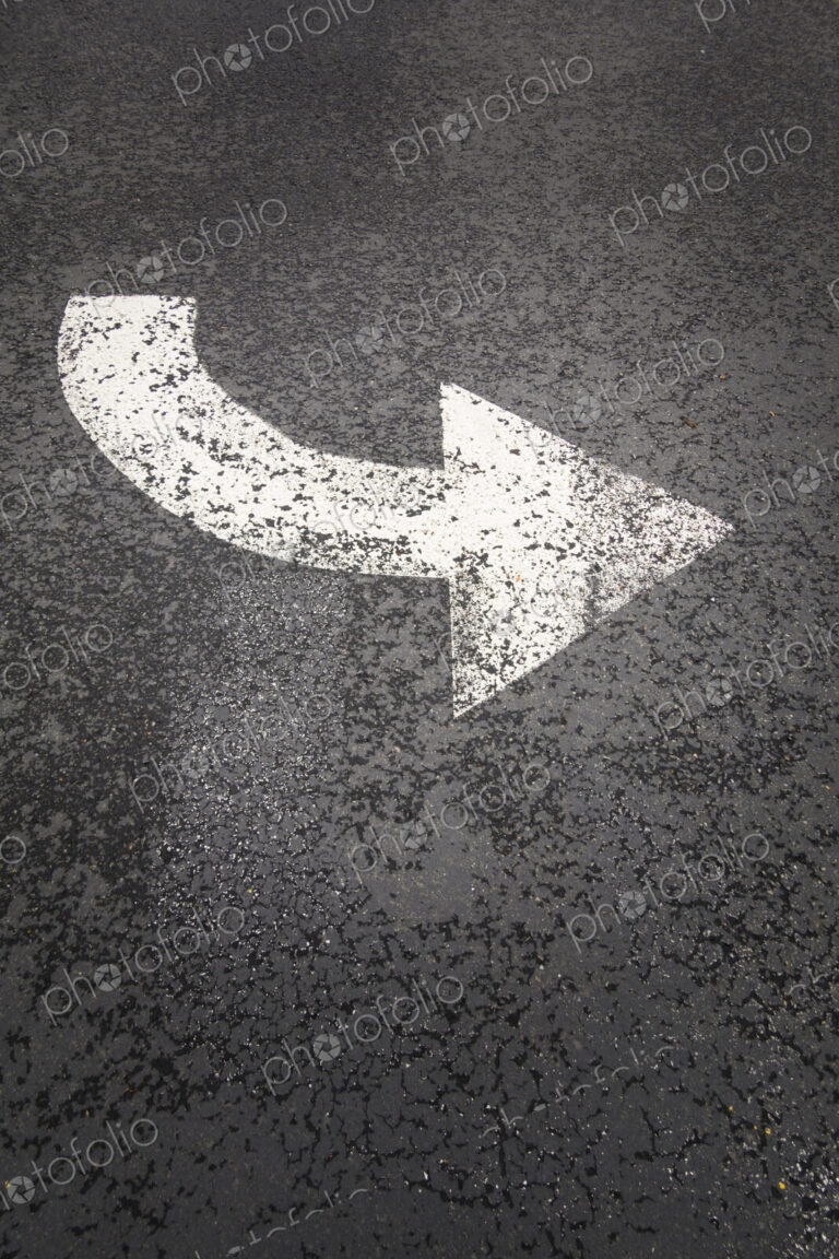 A white painted curving arrow symbol, a road marking on a road surface.