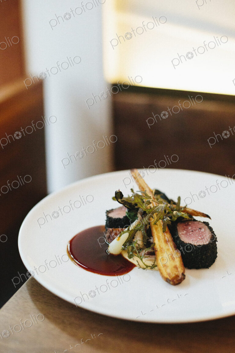 A white plate with a cooked dish of meat and vegetables.