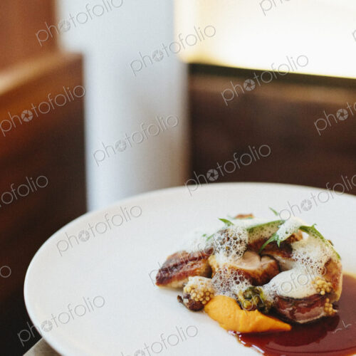 A white plate with a cooked dish of meat and vegetables.