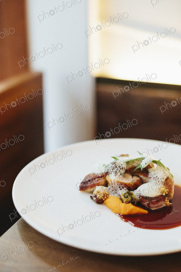 A white plate with a cooked dish of meat and vegetables.