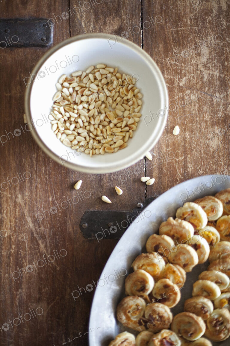 A white pottery bowl, full of dried corn kernels. A dish of baked pastries.