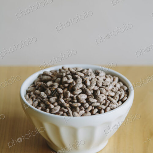 A white round china bowl of kidney beans on a table top. A white round china bowl of kidney beans on a table top.